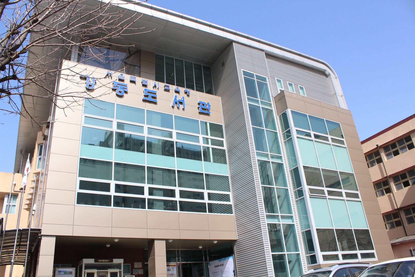 '강동도서관'이라고 파란 글자가 크게 붙은 건물이 파란 하늘 아래 서 있다.
