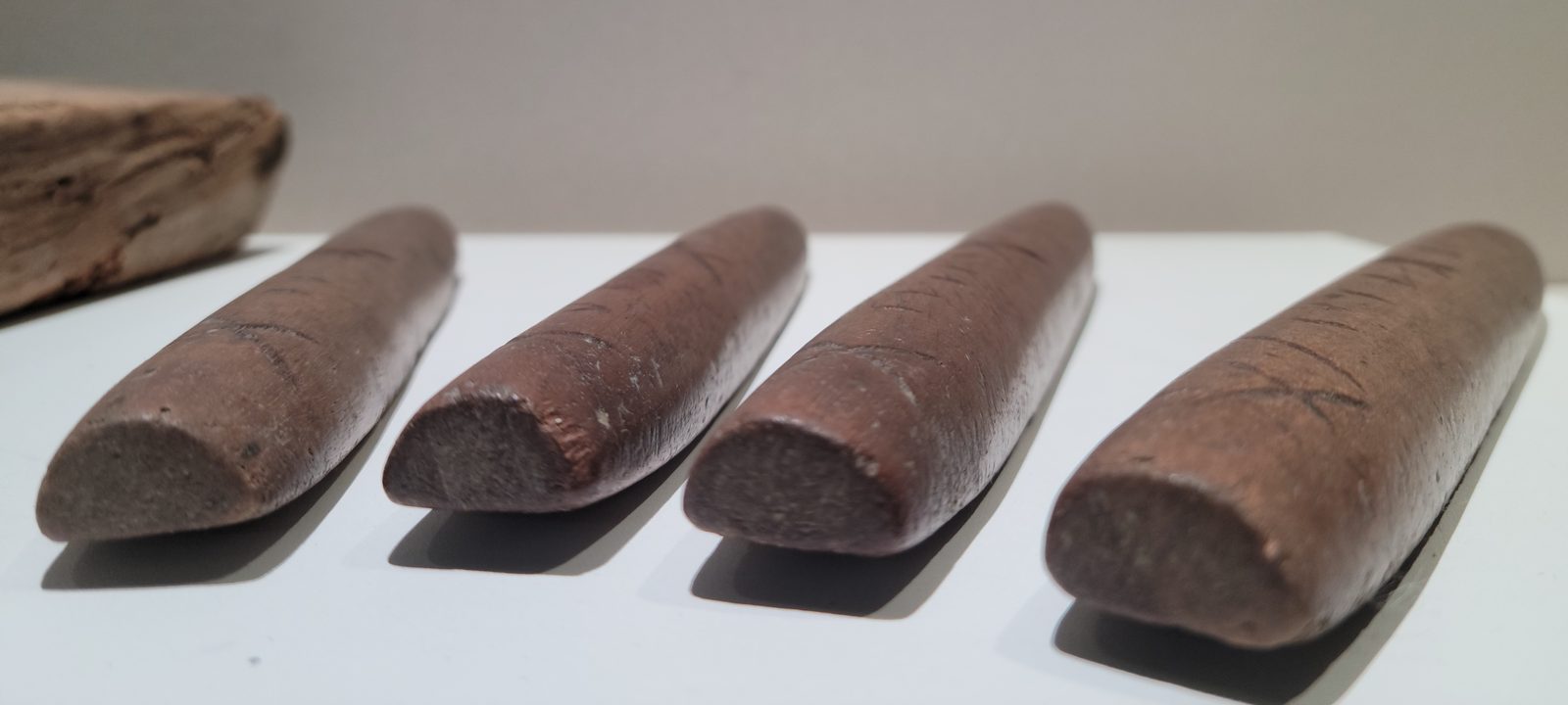 통나무를 반으로 쪼개 만든 윷 네 개가 나란히 놓여 있고, 등에는 칼로 새긴 금이 보인다.