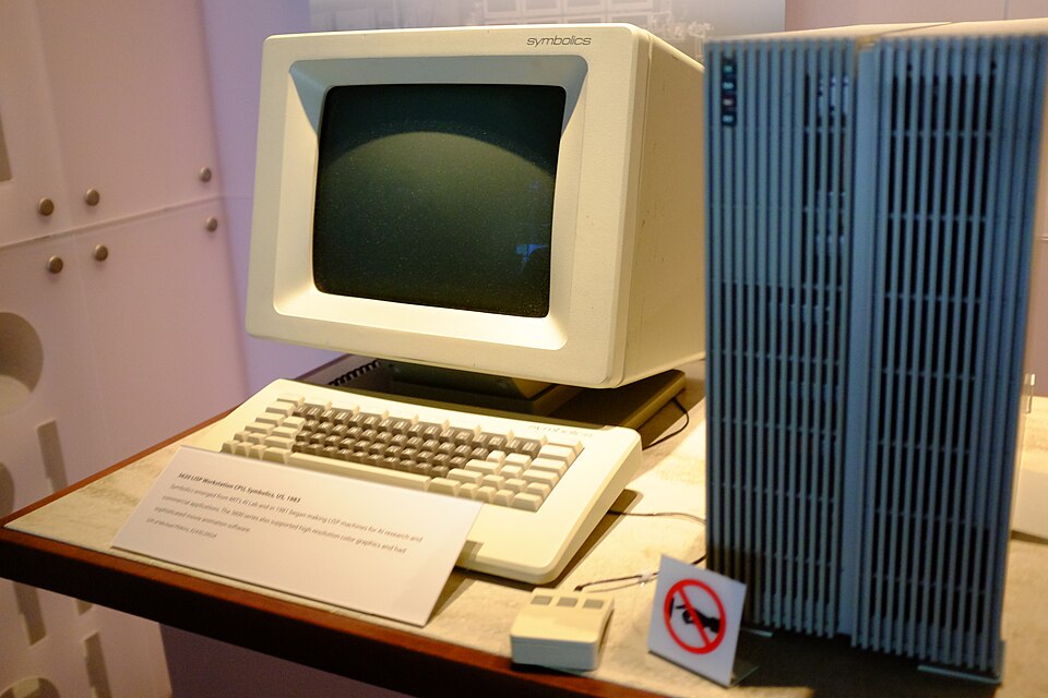 박물관 진열대 위의 Symbolics 리스프 워크스테이션 — 흰 모니터와 키보드, 마우스, 옆에 선 푸른 본체와 설명 팻말
